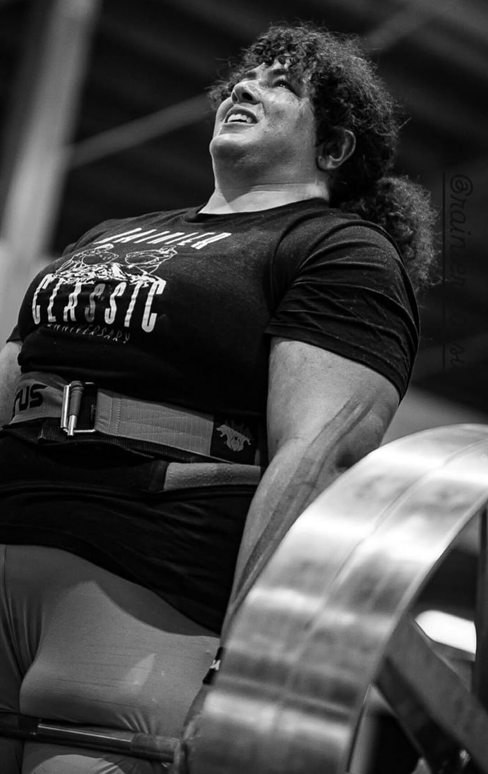 Strongwoman lifting heavy weights in a gym, showcasing power and determination in a competitive strongwoman event.