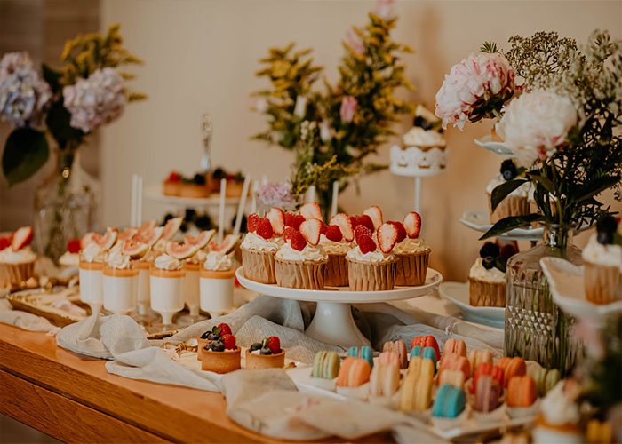 Elegant birthday party dessert table with cupcakes, macarons, and floral arrangements capturing celebration details.