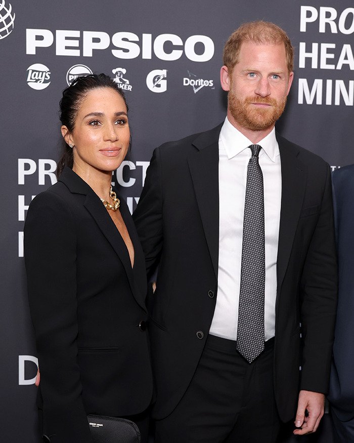 Meghan Markle and Prince Harry posing at a formal event, linked to Meghan Markle royal gesture controversy.