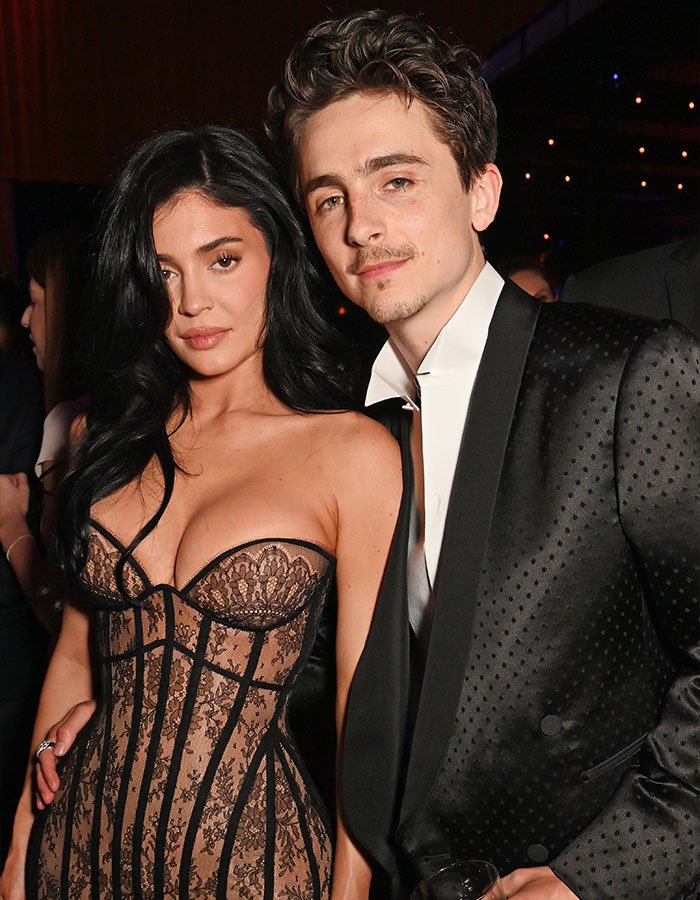 Timoth&eacute;e Chalamet posing at an event with a woman, sparking fans&rsquo; theory linking him to masked rapper EsDeeKid.
