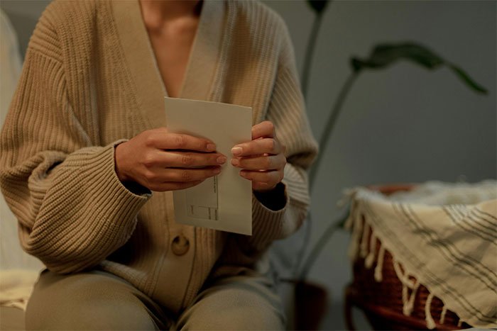 Woman in a cozy sweater holding a letter, illustrating a mom preventing solicitor contact about grandma’s inheritance.