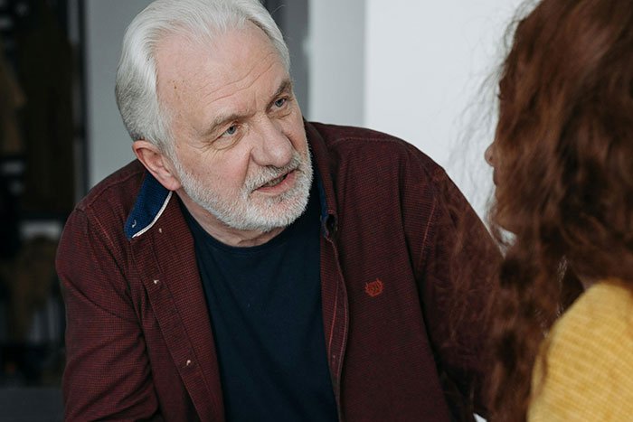 Older man appearing upset while talking to a younger woman, reflecting a selfish dad demanding apology after ruining Christmas memory.
