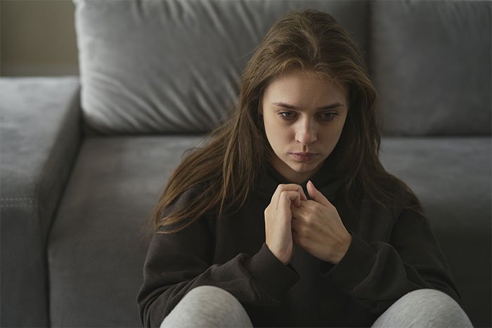 Teenage girl sitting alone looking worried, illustrating a mom preventing solicitor contacting daughter about inheritance.