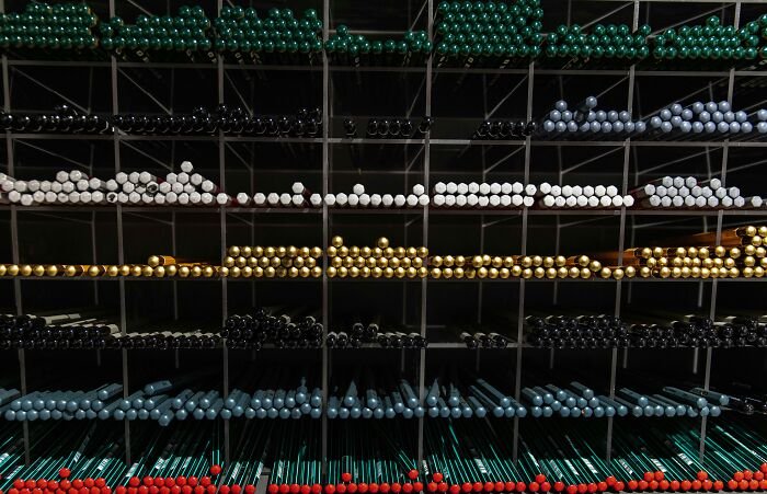 Rows of colored drumsticks arranged by color in a grid rack, challenging viewers to spot the connection.