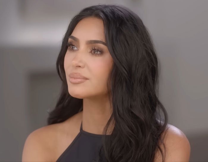 Kim Kardashian with long dark hair, reflecting on low brain activity after medical scan in an indoor setting.