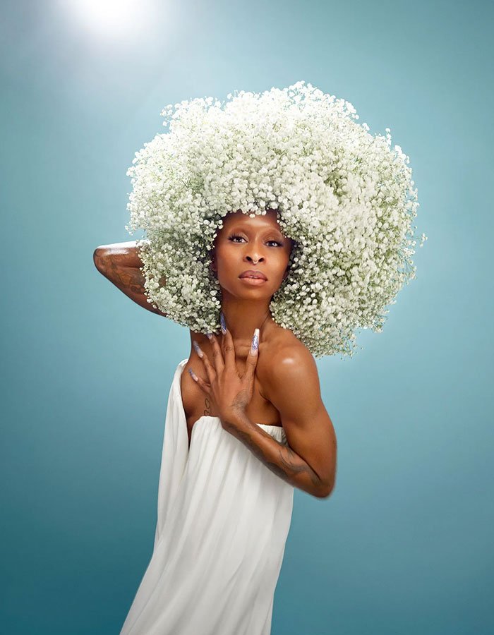 Cynthia Erivo posing in white dress with large floral headpiece, reflecting Ariana influence and Wicked For Good success.