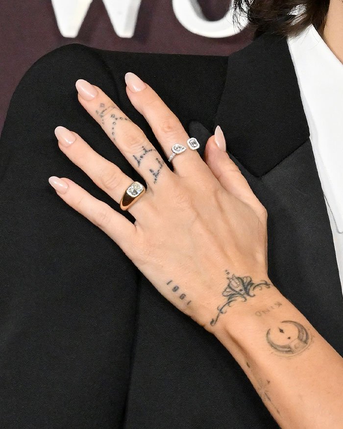 Close-up of hand with engagement rings and tattoos highlighting Miley Cyrus and Maxx Morando's engagement reaction.