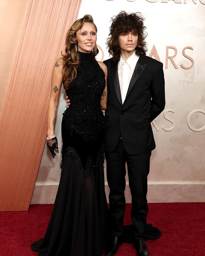 Miley Cyrus and Maxx Morando posing on the red carpet, engagement sparking mixed reactions about age difference.