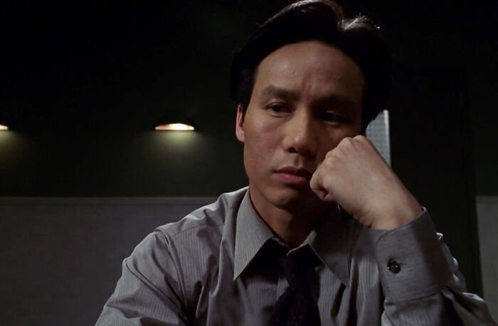 BD Wong from Jurassic World looks thoughtful and somber in a dimly lit room reflecting on his recent apology.