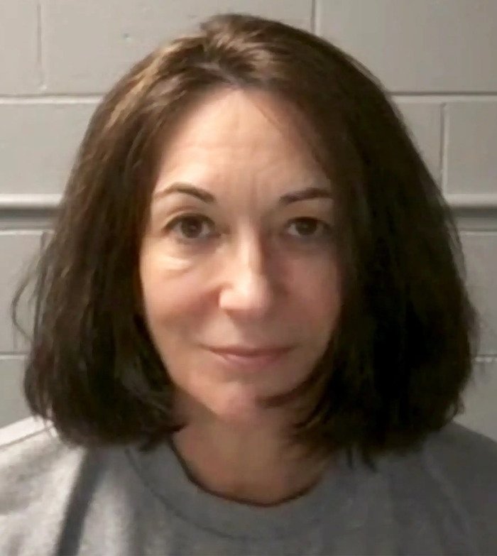 Woman with shoulder-length dark hair in front of a gray cinder block wall, relating to eerie new images of Epstein’s private island.