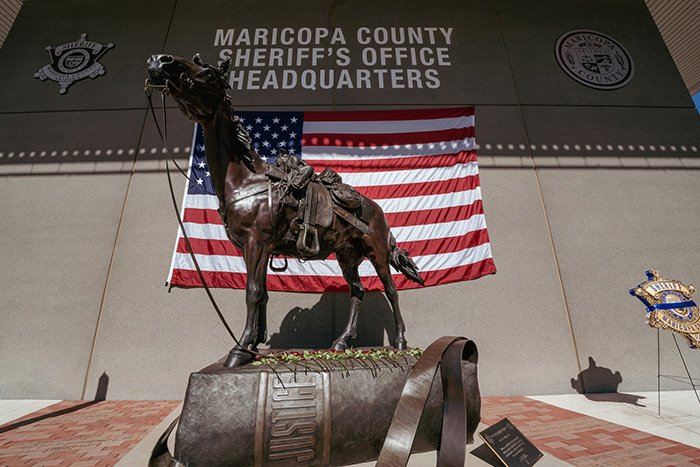 Statue outside Maricopa County Sheriff’s Office headquarters with American flag, linked to woman’s chilling 911 call case.