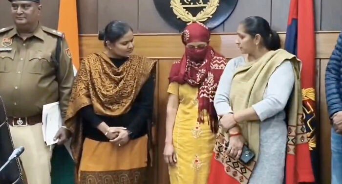 Woman in headscarf standing with family and police, linked to horrifying wedding tragedy and missing child's body discovery.
