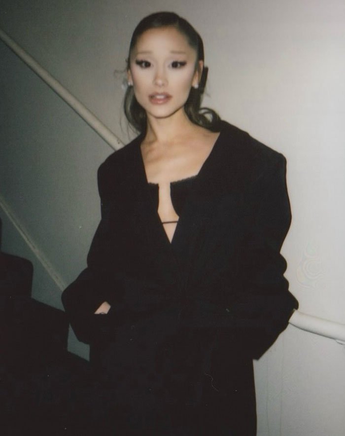 Ariana Grande wearing a black outfit posing indoors, with people noticing a bizarre detail in the photo shared by Rebel Wilson.