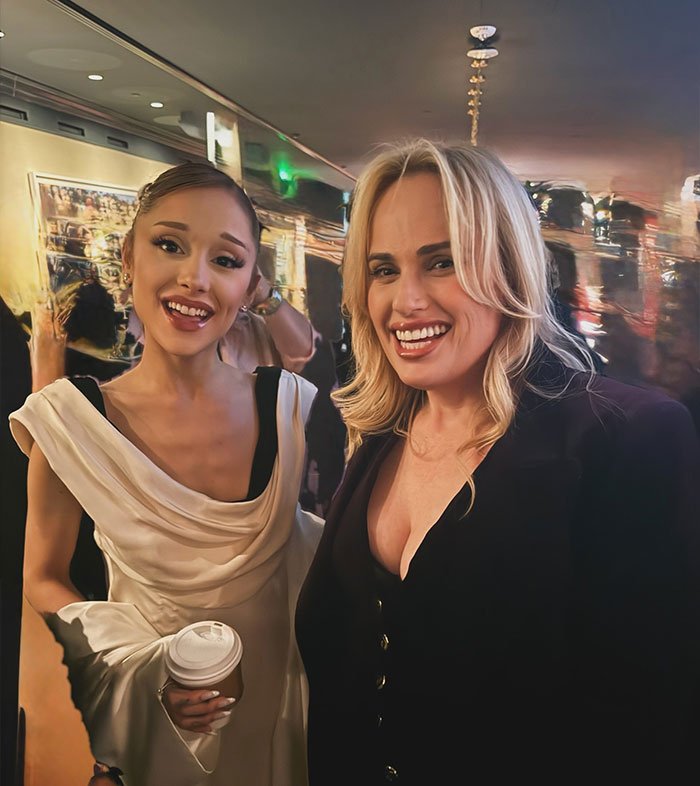 Rebel Wilson and Ariana Grande smiling together at an event with a bizarre detail noticed in the background.