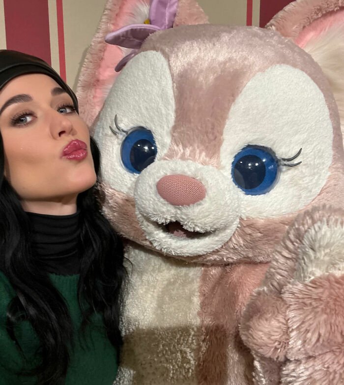 Woman posing with a large pink and white plush character, unrelated to Justin Trudeau and Japan's Ex-PM meeting.