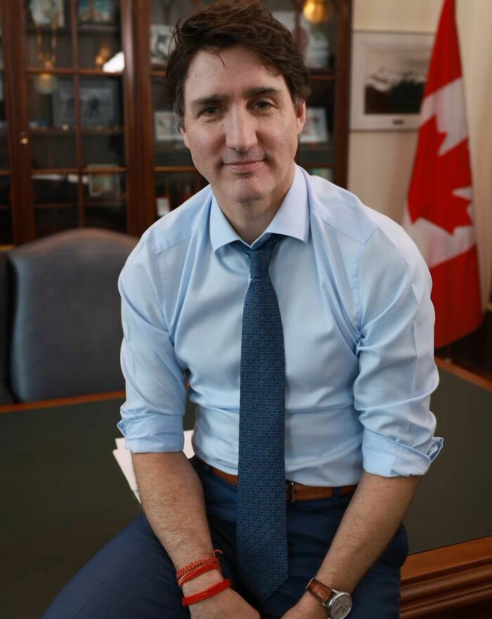 Justin Trudeau sitting casually in an office with Canadian flag, representing a meeting with Japan's Ex-PM and Katy Perry.