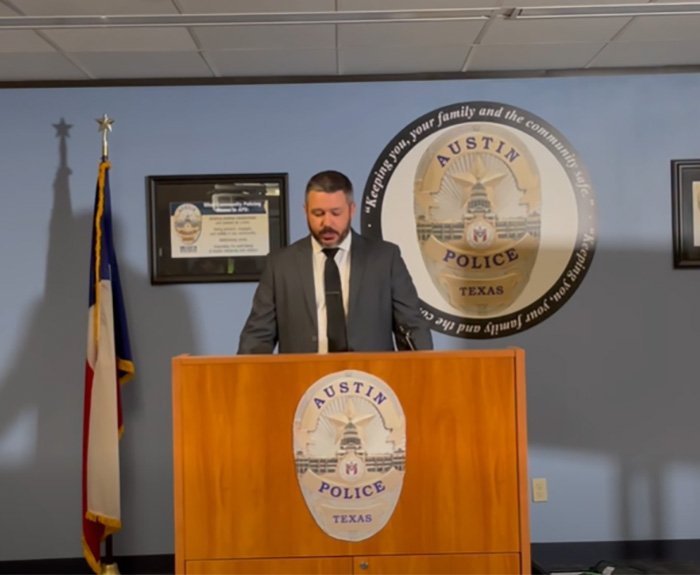 Austin police officer at podium during press briefing on crucial clue found on late cheerleader’s phone.