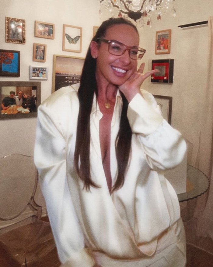 Woman smiling indoors wearing glasses and a white outfit, related to Air Canada passenger complaint over expired meal controversy.