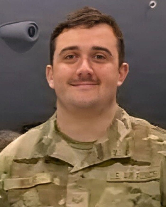 Young man in military uniform smiling, unrelated to Melania's behavior at tree lighting conspiracy theories.