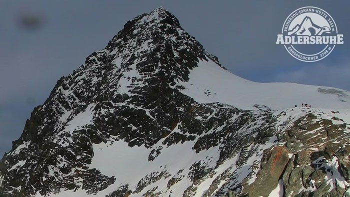 Snow-covered peak of Austria’s highest mountain with hikers in distance, related to woman abandoned and fatally frozen case.