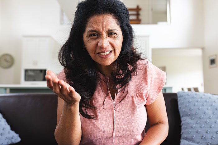 Woman showing frustration and anger in a home setting, illustrating teen’s struggle with stepmother insecurity issues.