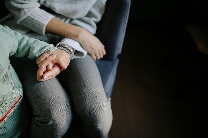 Teen and stepmother holding hands, capturing an emotional moment reflecting insecurity about a kid and family tension.