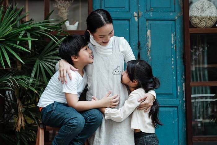 Mother warmly embracing daughter and son, unaware of how much her daughter is doing for her.