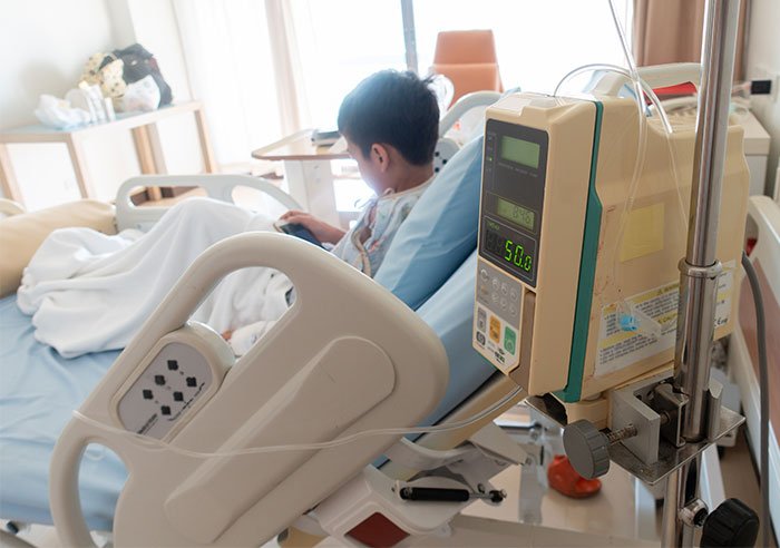 Child recovering in hospital bed after accidentally eating gummies, highlighting mom calls 911 and arrest debate online.
