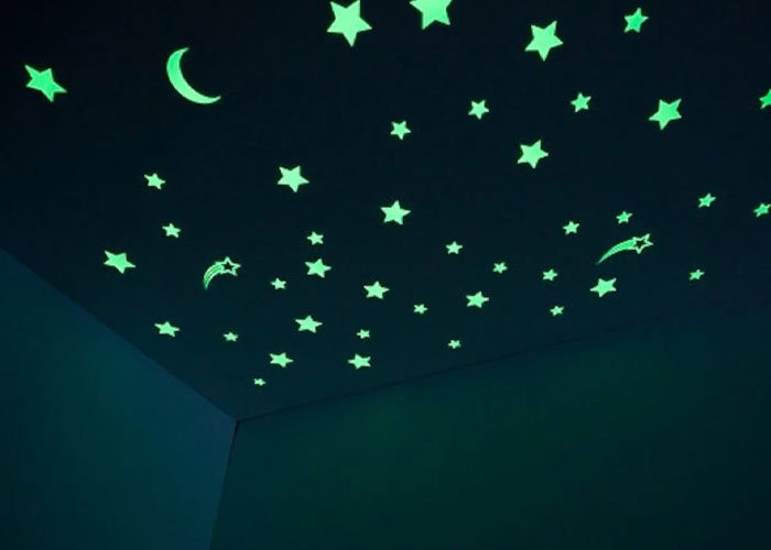 Glowing green stars and crescent moons on a dark ceiling illustrating a peaceful night sky scene.
