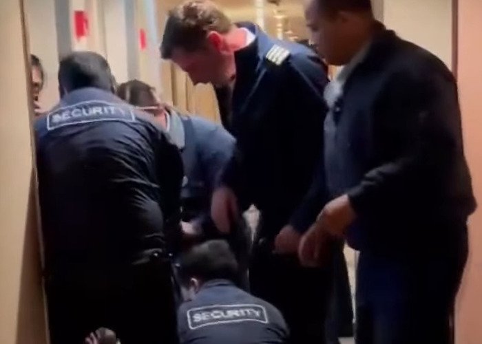 Security and crew members handling the cruise passenger's body after fatal overconsumption of drinks on board.