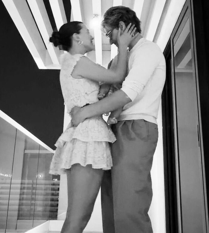 Couple embracing indoors in a modern setting, related to viral theory about Millie Bobby Brown's newborn daughter.