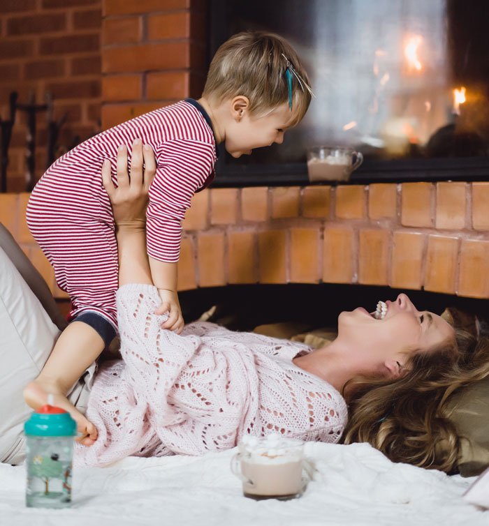 SAHM enjoying playful moment with child near fireplace, highlighting challenges faced when husband asks for divorce.