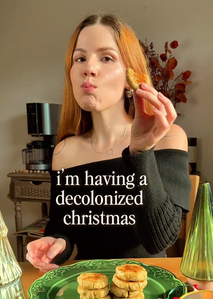 Young social media user eating cookies at table with festive decor, referencing decolonized Christmas trend.