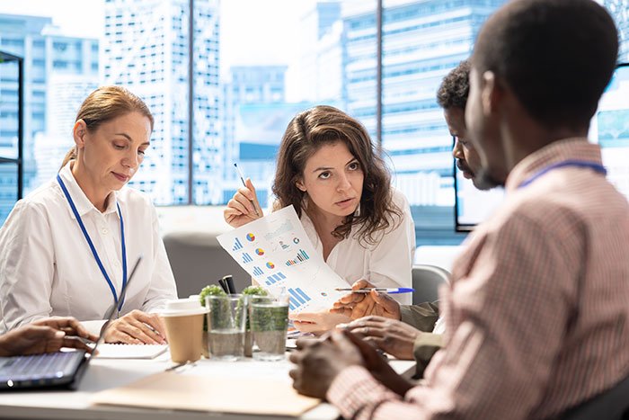 Business team analyzing charts and discussing subtle red flags that indicate job security concerns in an office setting.