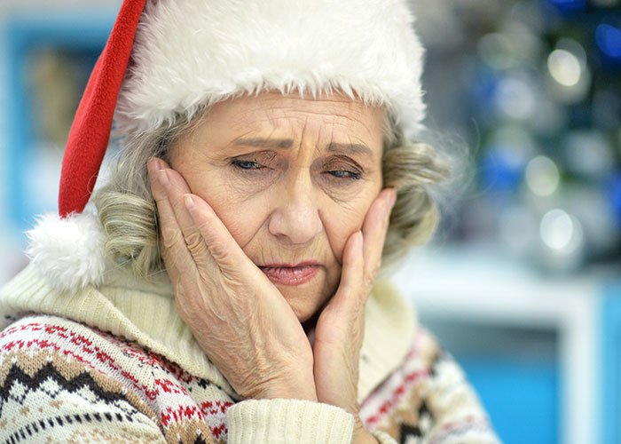 Elderly woman in a Santa hat looking upset and thoughtful, reflecting on son’s partner and gift issues.