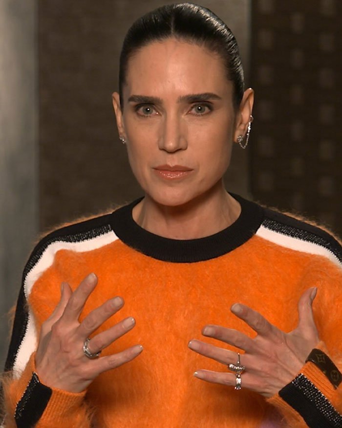 Jennifer Connelly in an orange sweater, discussing her regrets about an iconic movie scene sparking career debate.