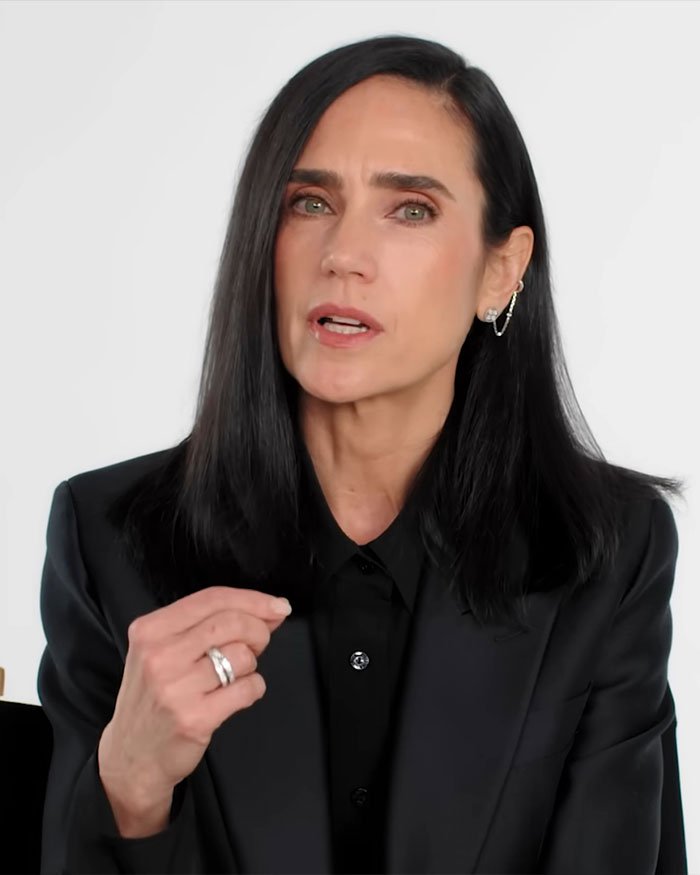 Jennifer Connelly speaking about iconic movie scene regrets in a black blazer with long dark hair on a white background.