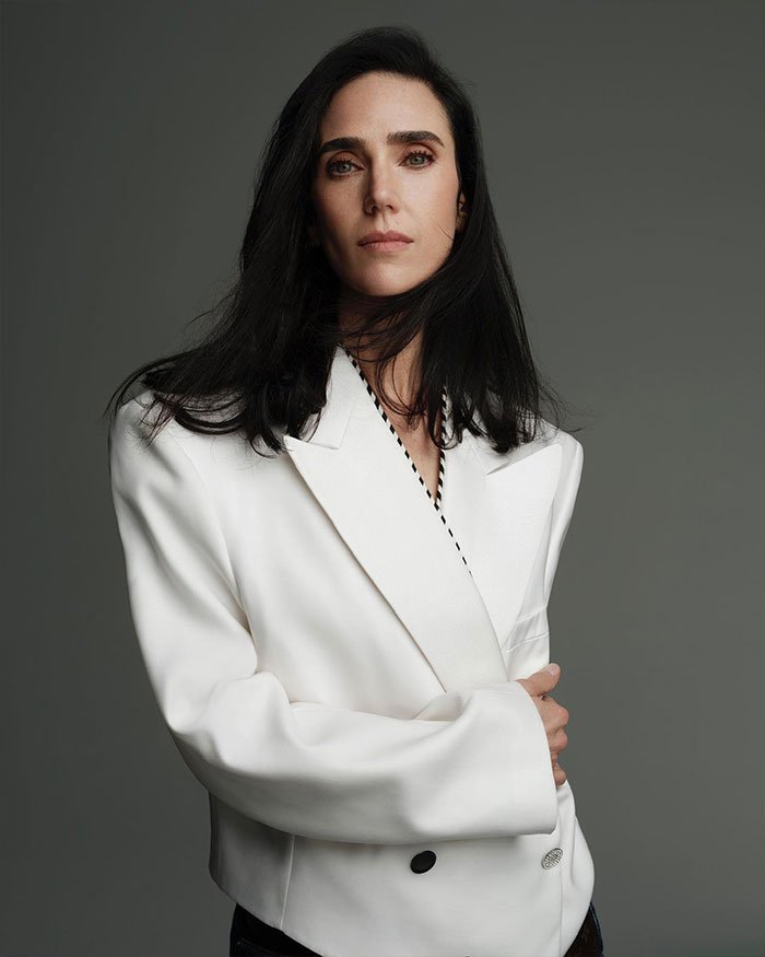 Jennifer Connelly posing confidently in a white blazer, reflecting on her iconic movie scene and career regrets.