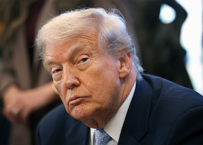 Donald Trump in a serious expression, wearing a suit and tie, amid controversy over post involving Rob Reiner and TDS.