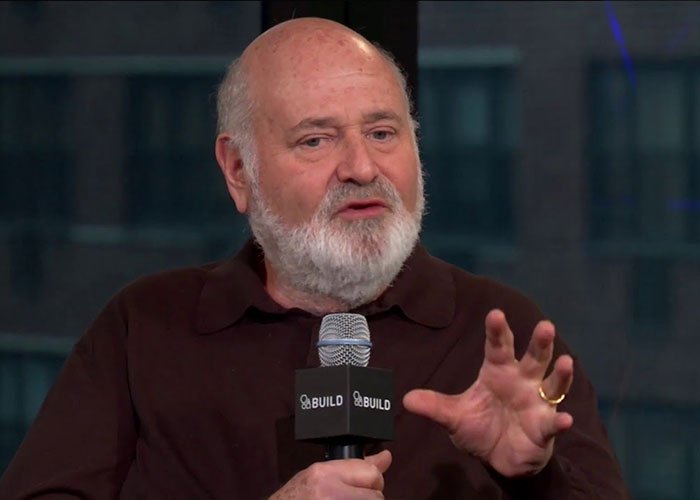 Rob Reiner speaking at a BUILD event, holding a microphone and gesturing while discussing political controversies involving Trump.
