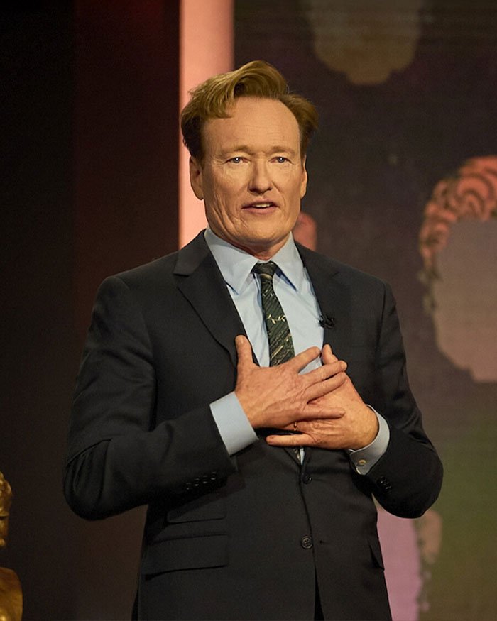 Man in a suit speaking on stage, with a focus on Rob Reiner and son Nick's fight before fatal incident.