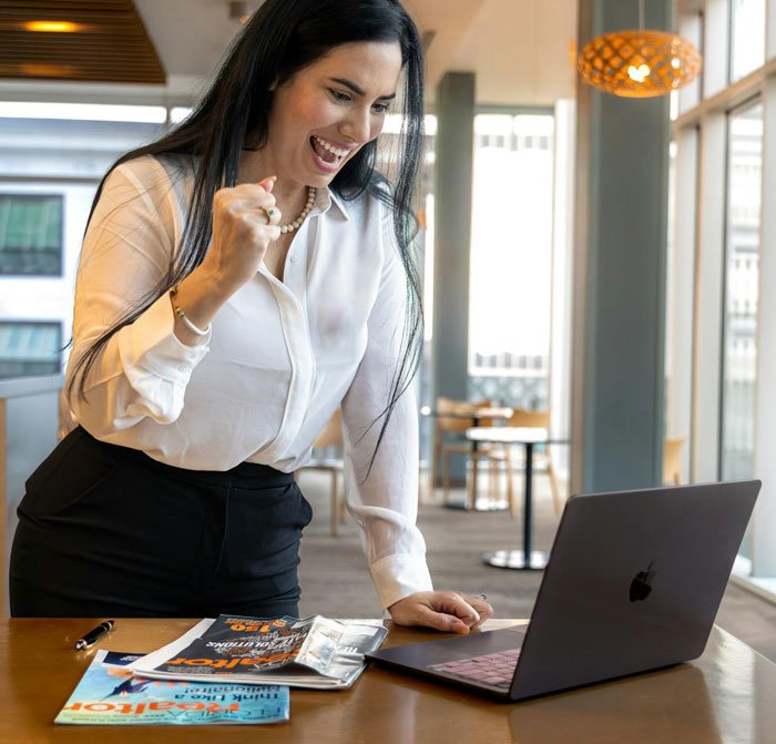 Young woman celebrating successful divorce news, working on laptop in bright modern office, related to divorce unexpected turn.