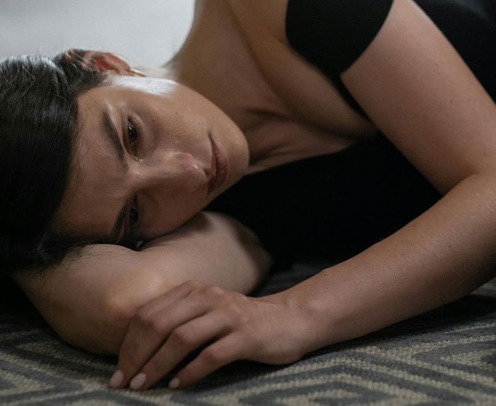 Sad woman lying down, reflecting on divorce and emotional struggles after man leaves wife for younger woman.