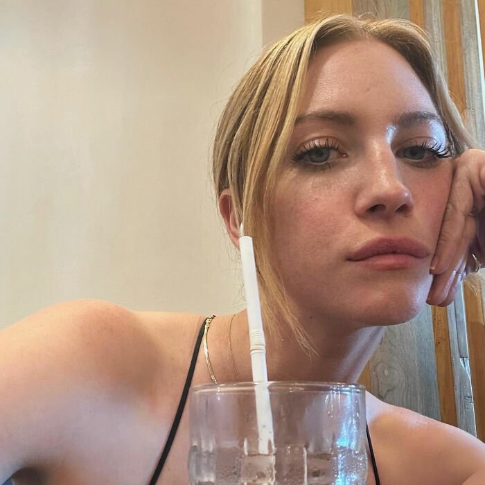 Britanny Snow with a neutral expression, resting her face on her hand near a glass with a straw, addressing plastic surgery rumors.