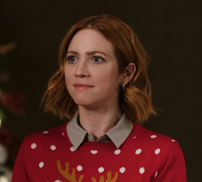 Britanny Snow with short red hair wearing a festive red sweater, responding to plastic surgery rumors in a candid moment.