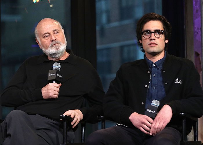 Rob Reiner and his son seated, holding microphones during a discussion about celebrities at Conan O'Brien's party.