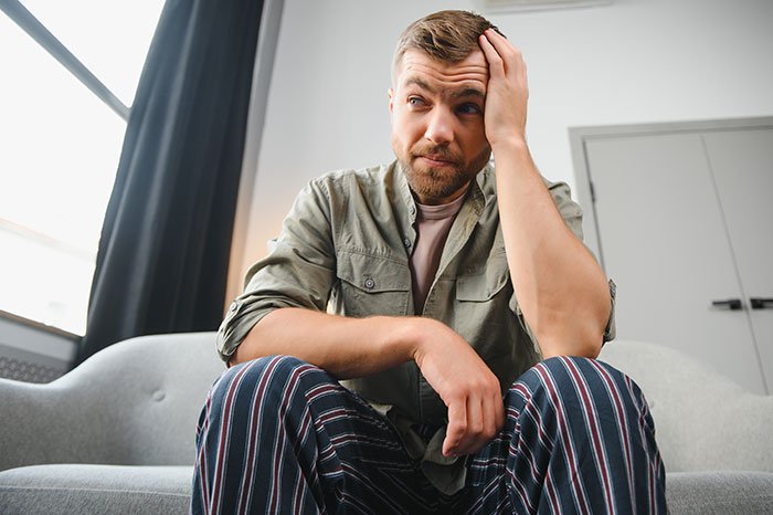 Man sitting on couch looking frustrated after lending girlfriend a spare keyboard, reflecting on her reaction.