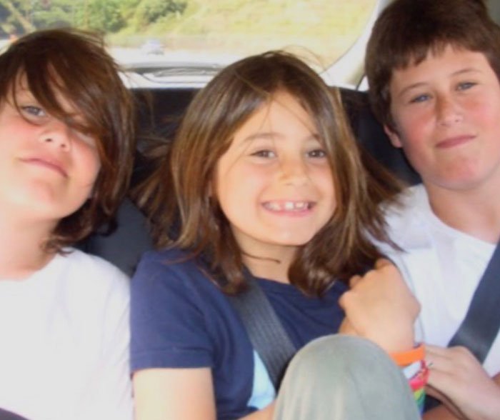 Three children of Rob Reiner sitting together in a car, smiling and wearing casual clothing.