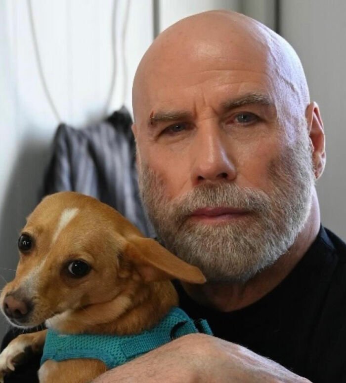 Bald man with beard holding small dog, illustrating bombshell court docs revealing Riley Keough as biological mother of John Travolta’s son Ben.