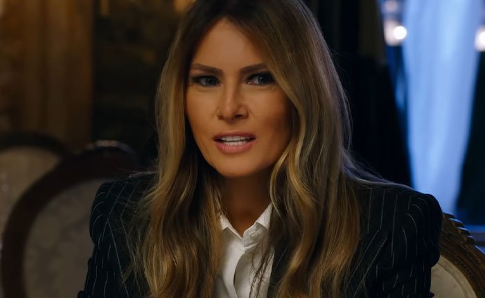 Melania Trump speaking in a pinstripe blazer and white shirt, featured in new documentary reactions discussion.